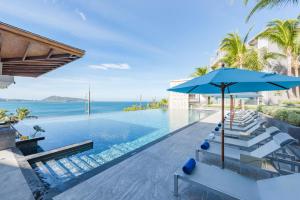 an infinity pool with chairs and an umbrella and the ocean at Oceanfront Beach Resort - SHA Extra Plus in Patong Beach