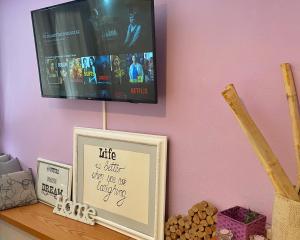 卡拉馬塔的住宿－Kalamata Home #2，粉红色墙壁上的电视,架子上的照片