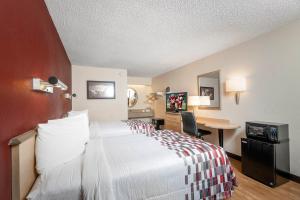 a hotel room with a bed and a desk at Red Roof Inn Buffalo - Niagara Airport in Williamsville