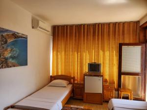 a bedroom with two beds and a television in it at Guest House Dzhegosh in Primorsko