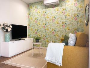 ein Wohnzimmer mit einem Sofa und einem TV in der Unterkunft Alojamento Batata in Nazaré
