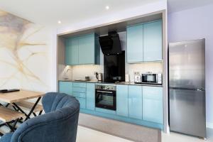 a kitchen with blue cabinets and a table and chairs at Stay for Work - Spotless and Stress-Free - Apartment 5 in Gillingham