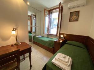 ヴェローナにあるAlla Villa Liberty Bed & Breakfastのベッド2台、テーブル、鏡が備わる客室です。