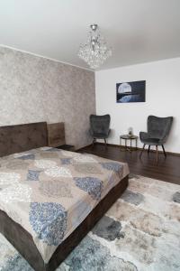 a bedroom with a bed and two chairs and a chandelier at Garsoniera LUX Drumul Taberei in Bucharest