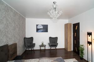 a living room with two chairs and a chandelier at Garsoniera LUX Drumul Taberei in Bucharest
