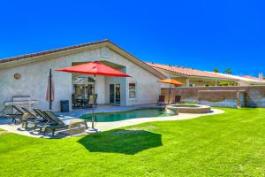 a house with a yard with a pool and an umbrella at Tranquil Times in Palm Desert