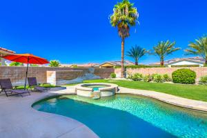 a swimming pool with an umbrella and a palm tree at Tranquil Times in Palm Desert