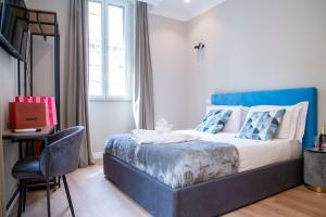 a bedroom with a bed with a blue headboard and a chair at AD Suites Tritone in Rome