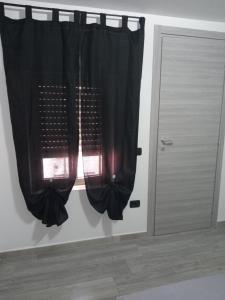 een raam met een zwart gordijn naast een deur bij Sea Paradise in San Giovanni