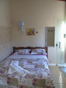 a bedroom with a bed with a blanket and a fan at Pousada Orquídeas da Canastra in Vargem Bonita