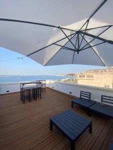 un balcone con tavoli, sedie e ombrellone di A-mare Exclusive Rooms & Suites a Taranto