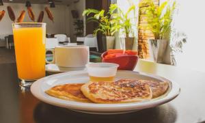 a plate of food with toast and orange juice on a table at Remfort Hotel in Santa Ana