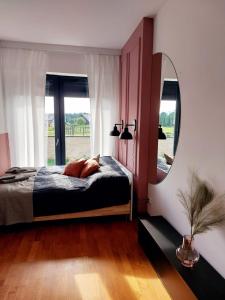 a bedroom with a bed with a mirror and a window at Apartament Panorama Park***** in Jelenia Góra