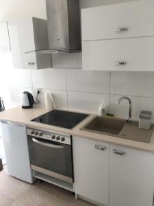 a white kitchen with a sink and a stove at Familly Apartament 4 in Międzyzdroje +3 photos