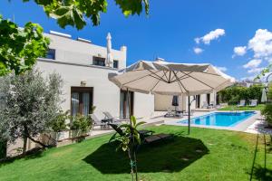 Gállos的住宿－Margo villa，享有带遮阳伞和游泳池的别墅的外部景致