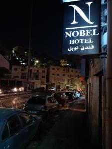 a sign for a hotel with cars parked in a parking lot at Nobel Hotel in Amman