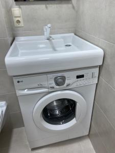 a white washing machine with a sink in a bathroom at Уютная квартира, в центре города in Tiraspol