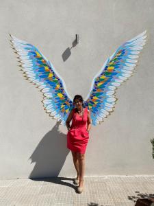 Una donna con un vestito rosso con le ali appese al muro di HOTEL Boutique ÁNGEL a Santa Cruz de Mudela