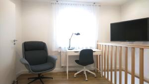 a room with two chairs and a desk and a television at Das Mini-Haus im Herzen Großostheims in Großostheim