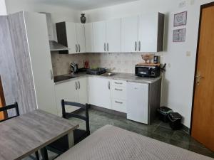 a small kitchen with white cabinets and a table at Apartma Juteršek 2+2 in Libeliče