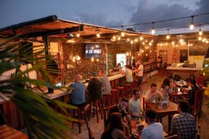 a group of people sitting at a bar in a restaurant at Che Playa Hostel & Bar Adults Only in Playa del Carmen