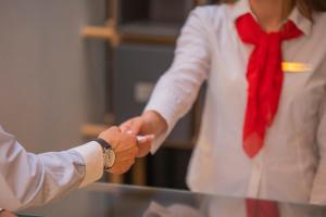 un uomo e una donna che stringono la mano mentre indossano una cravatta di Benelux Hotel a Pejë