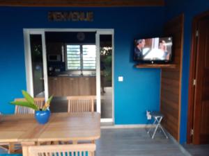 a dining room with a table and a tv on a blue wall at Villa charmante au Moule avec piscine in Le Moule