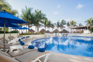 a beach with a pool, chairs, and a pool table at Hotel NYX Cancun in Cancún