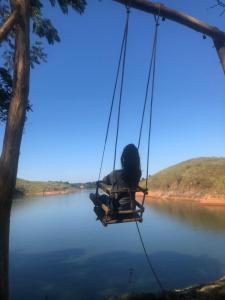 a person sitting in a swing over a lake at Bioevoluir in Igaratá