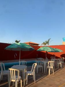 eine Reihe von Tischen und Stühlen mit Sonnenschirmen in der Unterkunft Rancho Itokazu in Delfinópolis