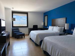 Holiday Inn Express Mérida, an IHG Hotel في ميريدا: غرفه فندقيه سريرين وتلفزيون