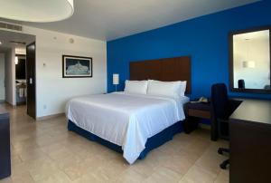 a bedroom with a bed and a desk and a blue wall at Holiday Inn Express Mérida, an IHG Hotel in Mérida