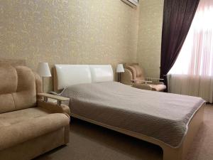 ロストフ・ナ・ドヌにあるアンジェリカ ホテルのベッドルーム1室(ベッド1台、ソファ、窓付)