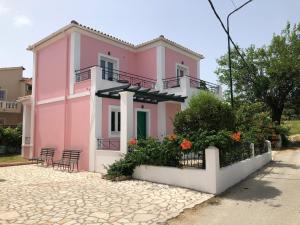 een roze huis met stoelen en bloemen ervoor bij Corfu Villa Mariù by Canal Damour Sidari in Melíssia