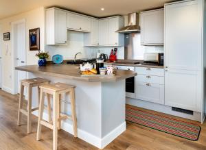 a kitchen with white cabinets and a counter with stools at Finest Retreats - Number Seven in Skipton