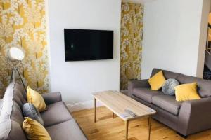 a living room with a couch and a table and a tv at WESTREACH Filey - a 4 Bedroom, all en-suite sleep 8 Townhouse in Filey