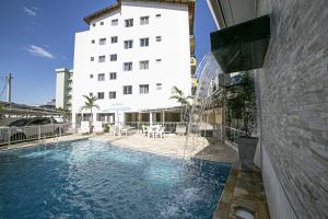una piscina di fronte a un edificio di Apto 22E ar condicionado e ventilador, 2 quartos, churrasqueira, elevador e piscina a Ubatuba