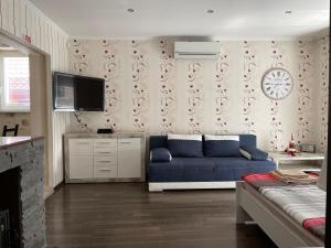 ein Wohnzimmer mit einem Sofa und einer Uhr an der Wand in der Unterkunft Apartmány Diana in Dunajská Streda