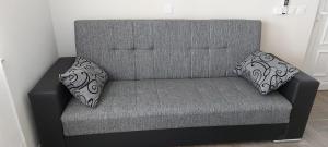 a gray couch with two pillows on top of it at Apartmani Katarina in Zadar