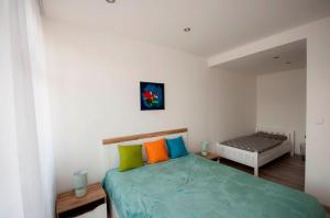 a bedroom with a bed with colorful pillows at MAYTEX - ubytovanie v 46m2 apartmáne s balkónom in Liptovský Mikuláš