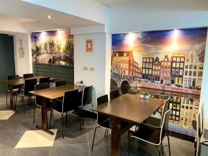 um restaurante com mesas e cadeiras e um quadro na parede em Xplore Hostel Amsterdam em Amesterdão