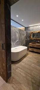 y baño con bañera y pared de piedra. en BnB La Cravache en Rekkem