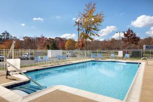 a swimming pool with chairs and a fence at Holiday Inn Express Dumfries-Quantico, an IHG Hotel in Dumfries