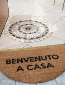 ein Schild, auf dem steht: Benvenuto a casa auf einem Fliesenboden in der Unterkunft La Maison de Miki in Lecco