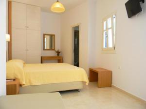 sypialnia z żółtym łóżkiem i oknem w obiekcie Anatoli Rooms w mieście Aegiali
