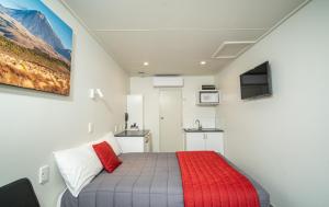 Welcome Inn Motel Levin في ليفين: غرفة نوم صغيرة مع سرير وبطانية حمراء