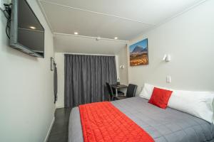 um quarto com uma cama com um cobertor vermelho em Welcome Inn Motel Levin em Levin