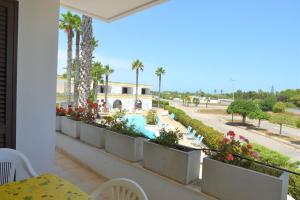 balcón con vistas a la piscina y a las palmeras en Residence Club Costa D'Oriente, en Torre dell'Orso