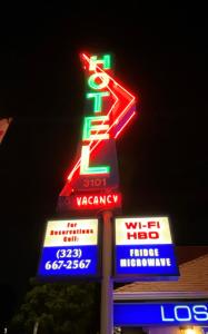 a sign for a gas station with neon signs at Los Feliz Hotel in Glendale