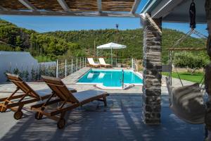 un patio con 2 sillas y una piscina en Villa Kyani, en Skopelos Town